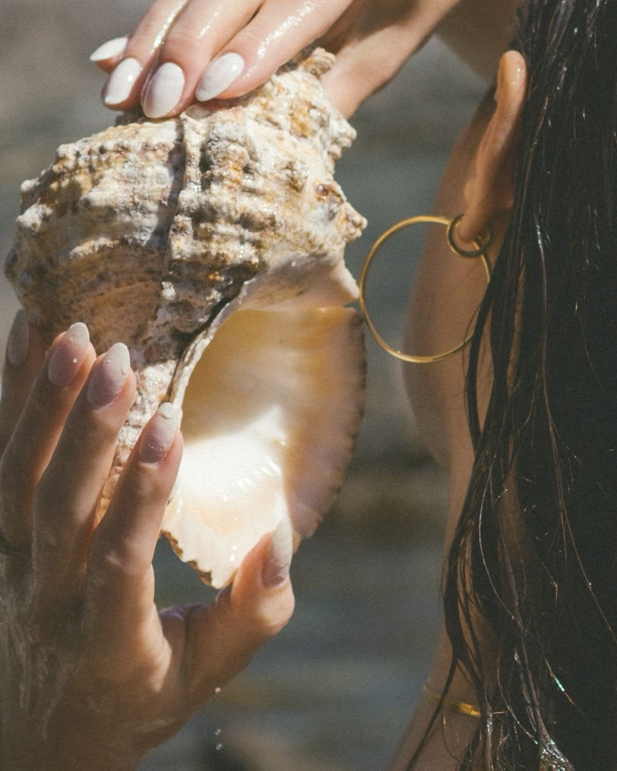 Mujer acercando una caracola marina al oído